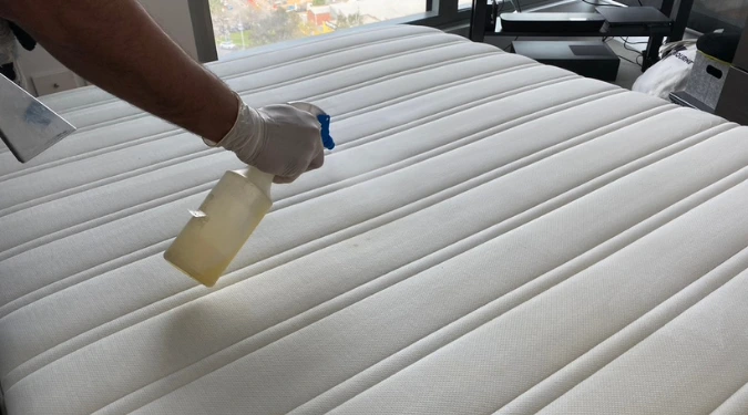 Man spraying water before Upholstery cleaning mattress